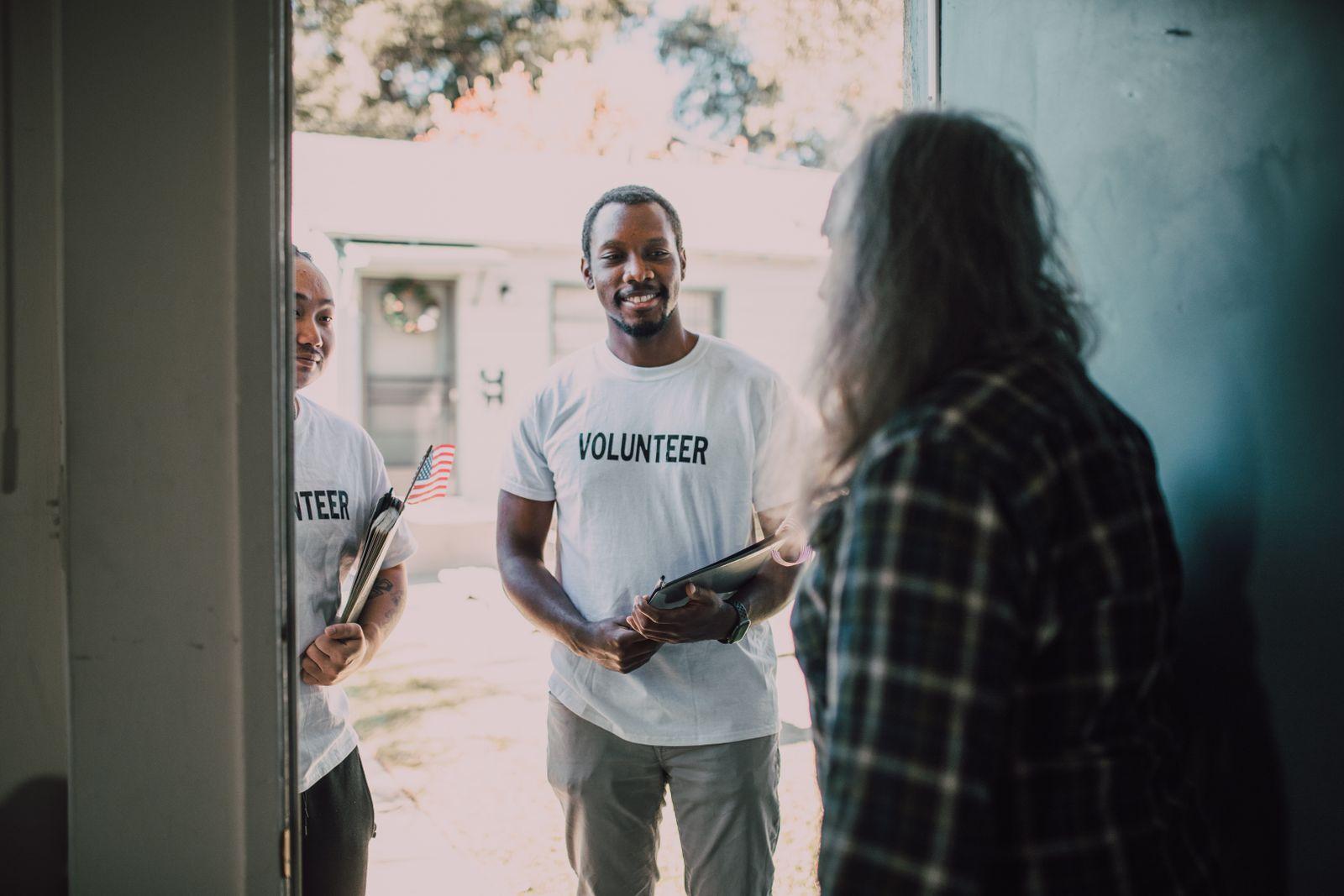 Volunteers with documents in hand visiting community members